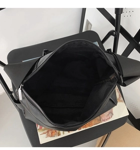 Detailed top view of a black tote bag main compartment with smooth zipper and wide strap