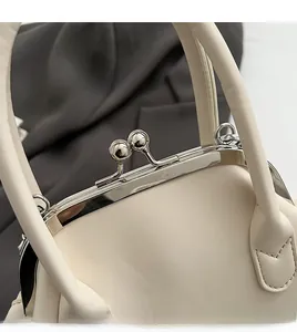 Close-up of vintage silver kiss-lock metal hardware on a cream luxury handbag