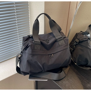 Detail of waterproof black nylon tote bag with matte hardware and shoulder strap