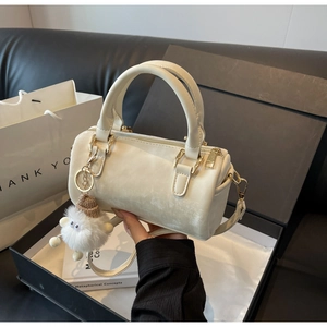 Close-up of cream Boston bag with matte finish and plush decorative charm details