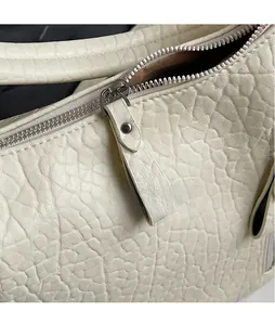 Détail de la fermeture éclair argentée et cuir grainé sur le sac fourre-tout crème