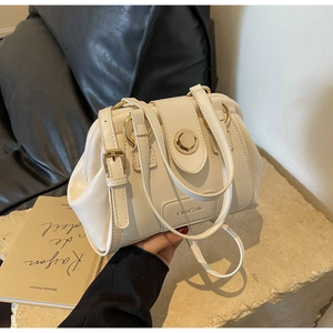 Close-up of cream-white cloud pleated Boston bag with gold ring clasp and brand tag