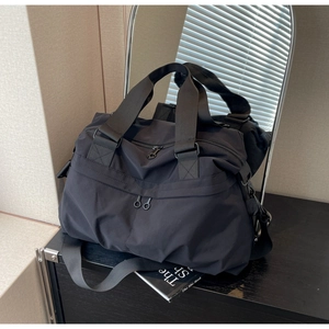 Detail of black nylon tote with durable dual-way metal zippers and adjustable shoulder strap