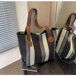 Close-up of large canvas tote bag with vertical stripes and brown reinforced straps