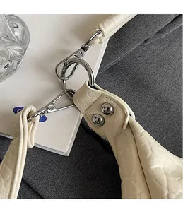 Détail du crochet argenté et du cuir texturé sur un sac fourre-tout vintage beige