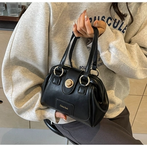 Detail of vintage black Boston bag featuring round gold metal handles and twist-lock closure