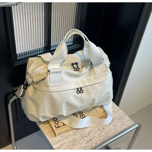 Close-up of cream nylon tote bag with reinforced handles and ring-pull zippers