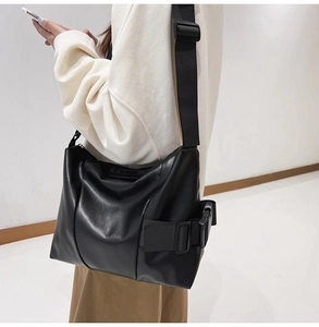 Detail of black tote bag featuring wide adjustable strap and side buckle closure