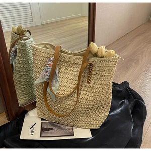 Detail of hand-woven beige tote bag with brown leather handles and floral silk scarf charm