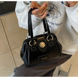 Detail of black Boston bag with gold circular twist lock and smooth leather texture