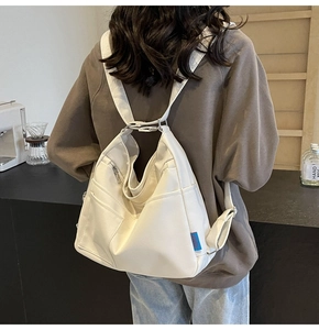 Close-up of white large-capacity tote bag with silver zippers and blue brand label