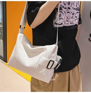 Close-up of white tote bag featuring wide adjustable strap and black plastic buckle