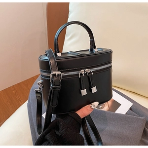 Détail du sac seau noir en cuir avec fermetures éclair argentées et poignée supérieure