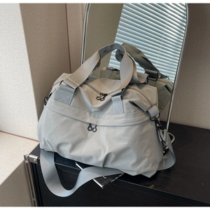 Detail of dark grey nylon tote showing reinforced handles and circular zipper hardware