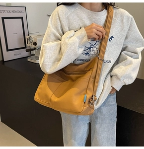 Close-up of yellow nylon tote bag with blue accent tag and wide shoulder strap