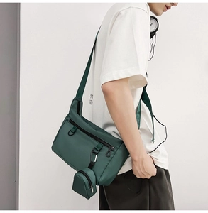 Detail of dark green canvas messenger bag with detachable mini pouch and metal zipper