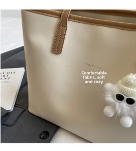 Detail of comfortable off-white tote bag with soft fabric texture and plush pendant