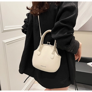 Close-up of a cream faux leather doctor-style bag with metal clasp and shoulder strap