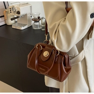 Detail of vintage brown doctor bag featuring polished faux leather and gold metal buckle