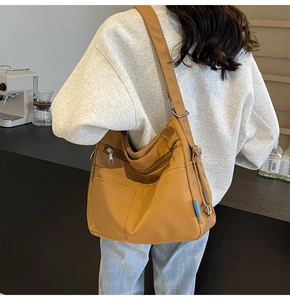 Detail of camel nylon tote bag showing multiple zipper compartments and utility pockets