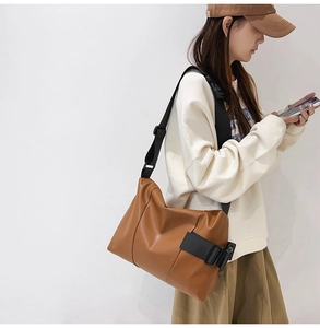 Detailed view of brown tote bag with wide nylon strap and large buckle for crossbody wear