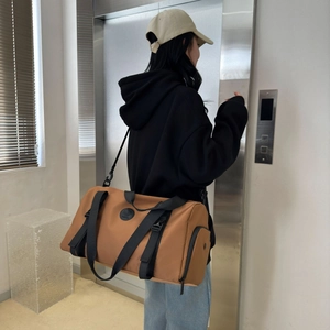 Detailed view of brown travel duffel bag with black straps and side zipper compartment
