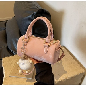 Detail of light pink Boston bag featuring a plush charm and gold hardware accents