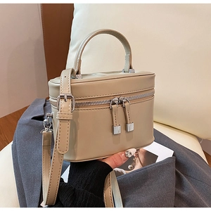 Détail du sac seau beige avec fermetures éclair argentées et poignée supérieure
