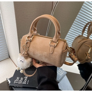 Detail of beige mini Boston bag with plush monster charm and gold metal hardware