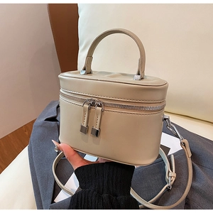 Détail du sac seau cylindrique blanc cassé avec double fermeture éclair et poignée cuir