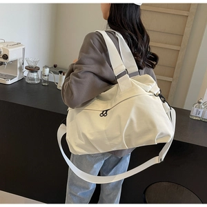 Close-up of durable cream nylon tote bag featuring reinforced straps and side pocket
