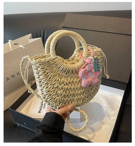Detail of woven straw handbag with drawstring lining and pink flower charm in a gift box