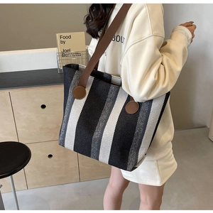 Detail of striped canvas tote bag showing textured vertical stripes and brown shoulder strap