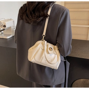 Chic cream Boston bag with cloud pleats and gold clasp, styled on a model's shoulder
