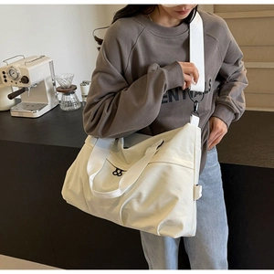 Detail of off-white canvas tote bag with wide straps and minimalist black circle logo