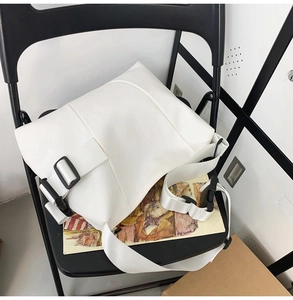 Detailed view of the white minimalist messenger bag featuring a bold black plastic buckle