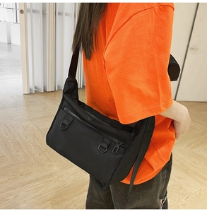 Close-up of black crossbody messenger bag with metal D-rings and double zipper pockets