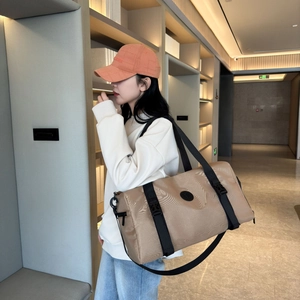 Spacious khaki Oxford travel bag with black shoulder strap shown on model in studio