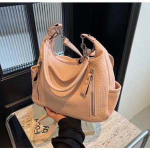 Détail du sac hobo en cuir grainé rose clair avec doubles anses et finitions argent