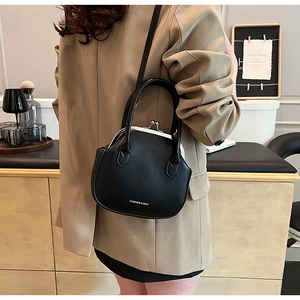 Detail of a vintage black leather doctor bag with metal clasp and top handle on a model