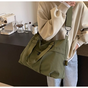 Army green nylon tote bag featuring wide canvas straps and black matte metal hardware details