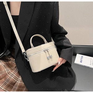Gros plan d'un mini sac seau beige porté en bandoulière avec détails en métal argenté