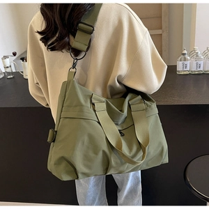 Olive green large nylon tote bag shown on model in a cozy cafe setting for daily commuting