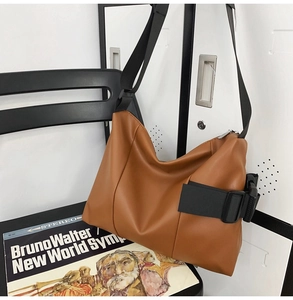 Detailed view of brown PU leather tote bag featuring a black wide strap and side buckle