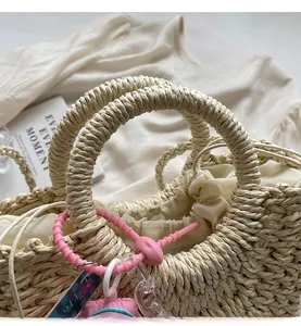 Close-up of woven straw bag with thick spiral handles and pink beaded charm