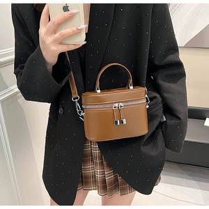Mini sac vanity en cuir marron avec détails argentés porté par un mannequin en studio