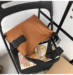 Detail of the brown PU leather tote bag featuring a black nylon strap and plastic buckle