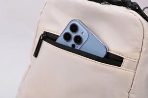 Detail shot of travel bag's front pocket showing storage capacity with a smartphone