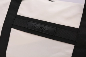 Detailed close-up of water-resistant oxford fabric and leather logo patch on travel bag