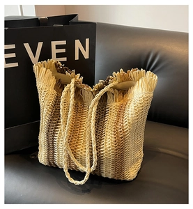 Detailed close-up of straw woven tote with fringe edges and rope handles for beach